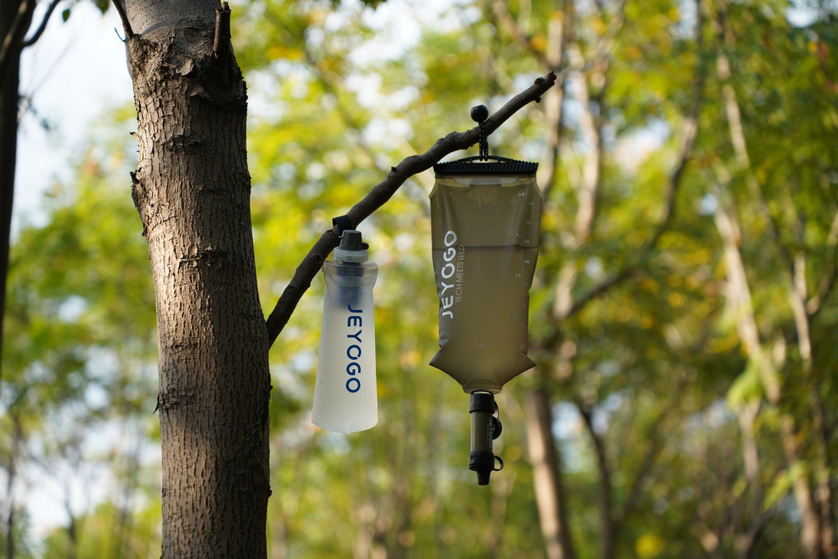 JEYOGO 2L gravity filtration reservoir suspended from a branch with a ball bungee cord.
