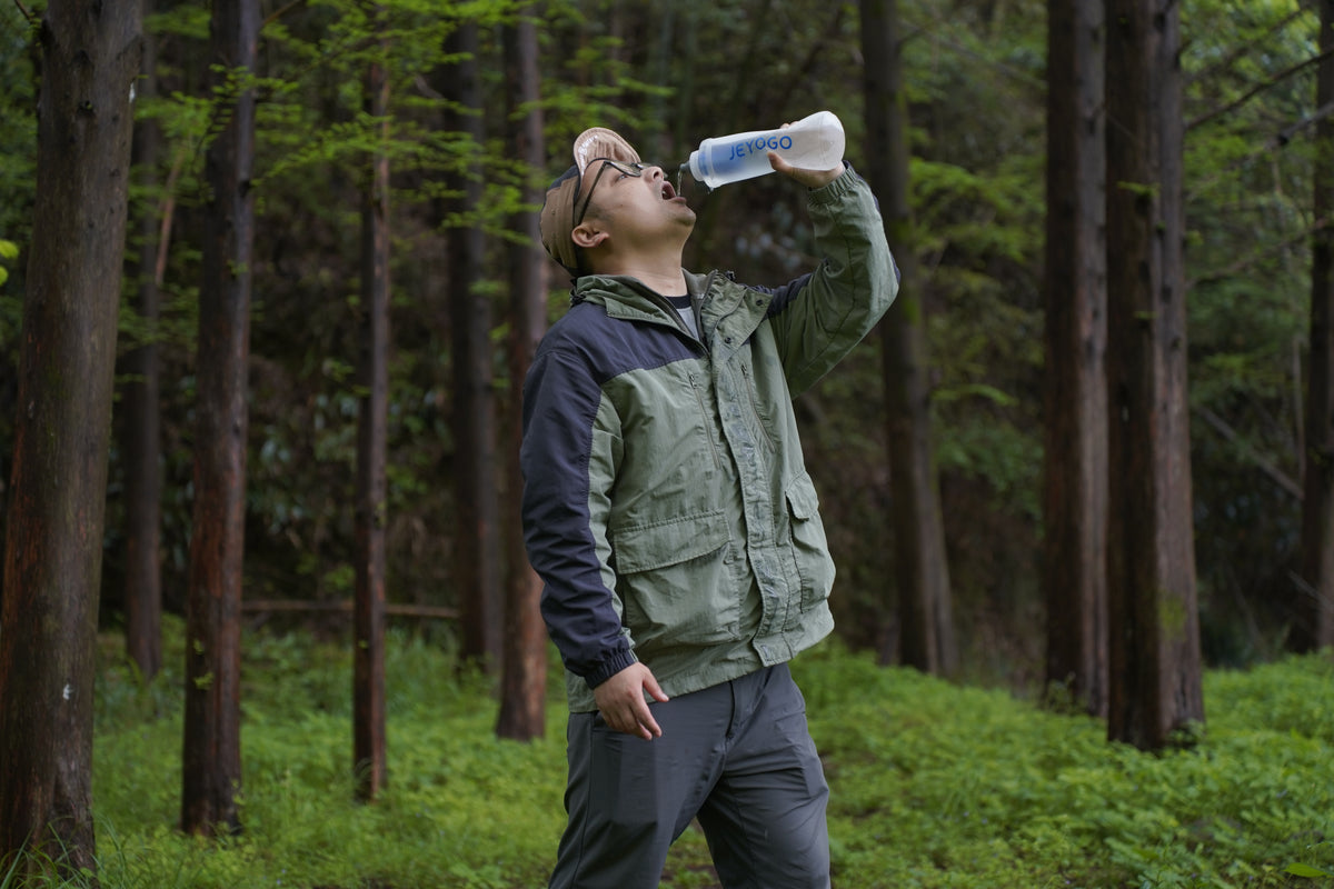 Drinking from the JEYOGO water filter bottle in a forest