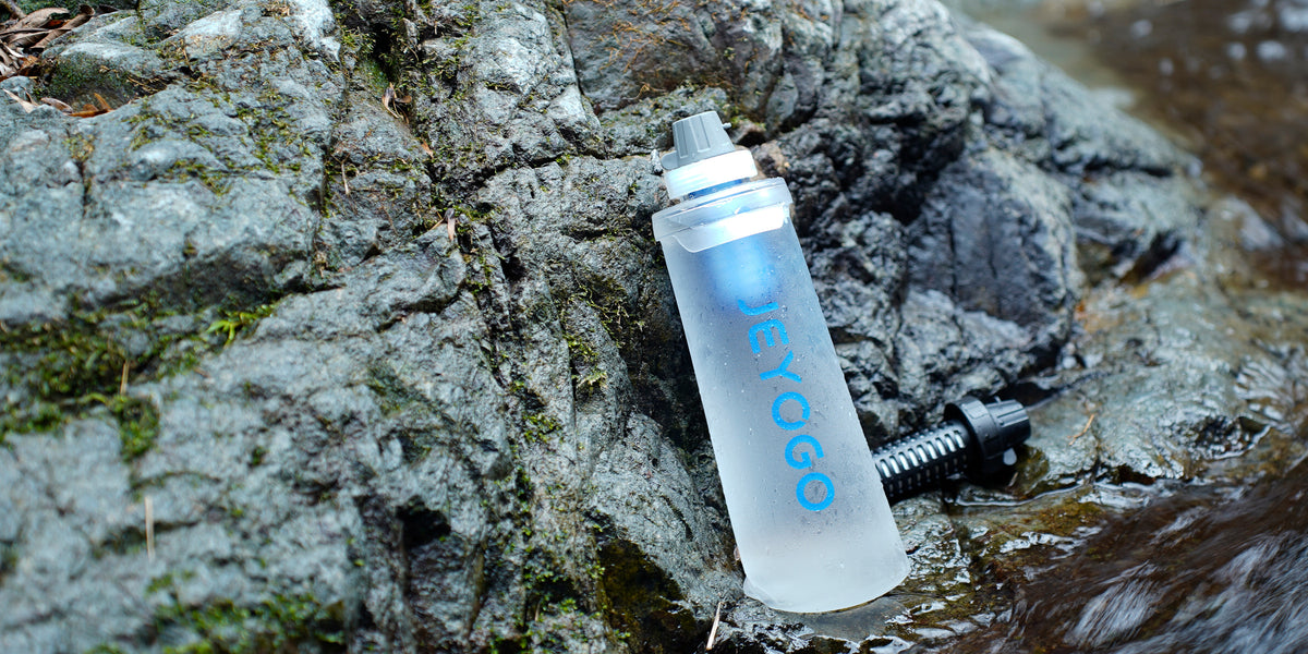 JEYOGO water filter bottle beside a rocky stream